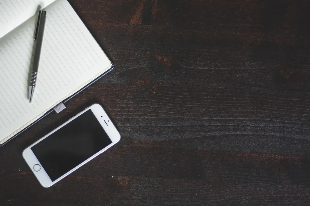 Smartphone modern diletakkan di atas meja kerja kayu dengan secangkir kopi